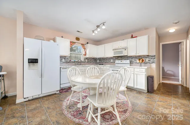 a kitchen with stainless steel appliances granite countertop a dining table chairs refrigerator and sink
