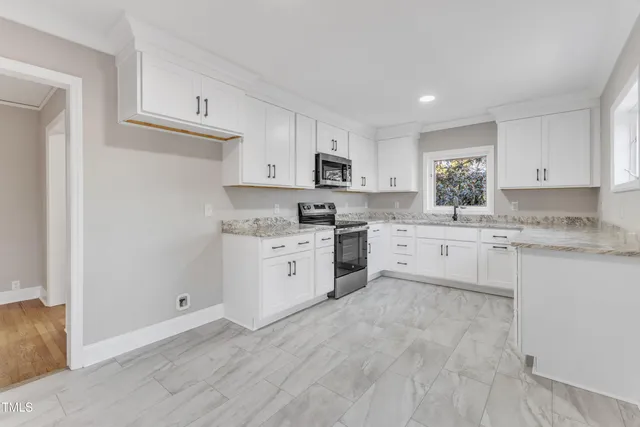 a kitchen with granite countertop white cabinets sink and stainless steel appliances
