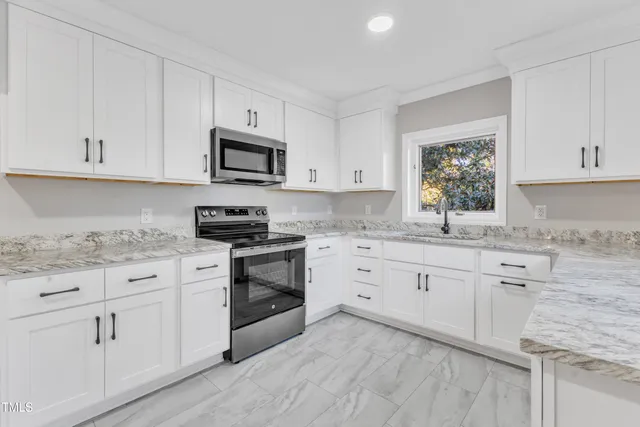 a kitchen with granite countertop white cabinets white stainless steel appliances with a sink and dishwasher