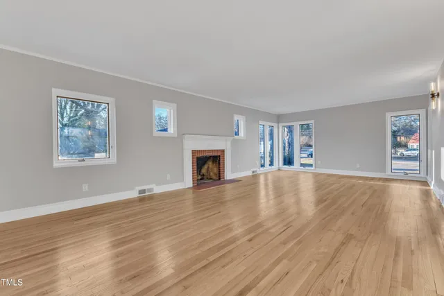 a view of empty room with wooden floor and fireplace