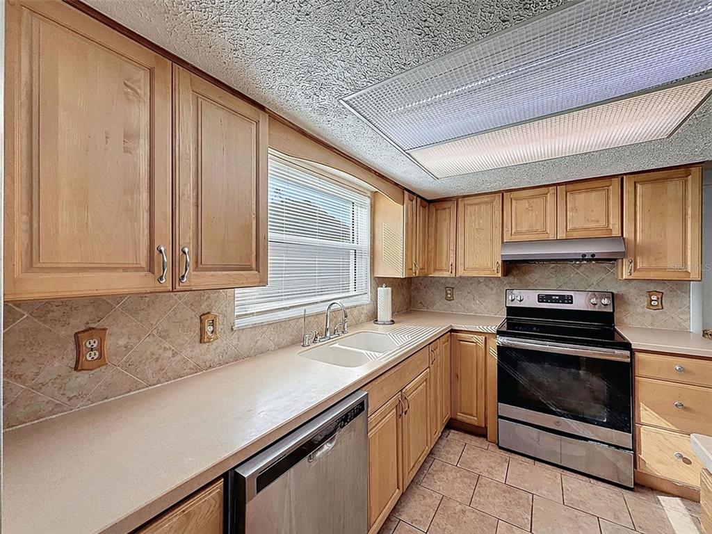 9610 Rainbow Lane Port Richey, FL 34668 - Photo 14 of 34 a kitchen with stainless steel appliances granite countertop a sink stove and cabinets