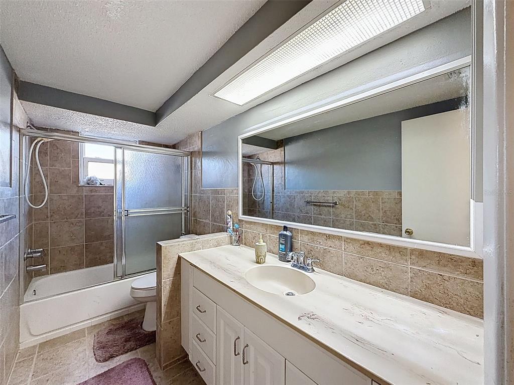 9610 Rainbow Lane Port Richey, FL 34668 - Photo 21 of 34 a bathroom with a granite countertop sink a toilet a mirror and shower