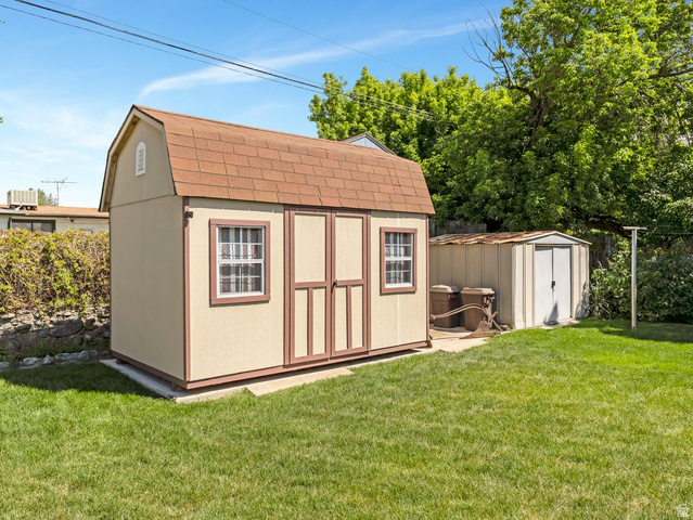 1502 North 475 West Sunset, UT 84015 - Photo 22 of 23 Spacious backyard featuring a gambrel-roof storage shed with dual double doors and two windows, a secondary metal storage shed, and a verdant lawn
