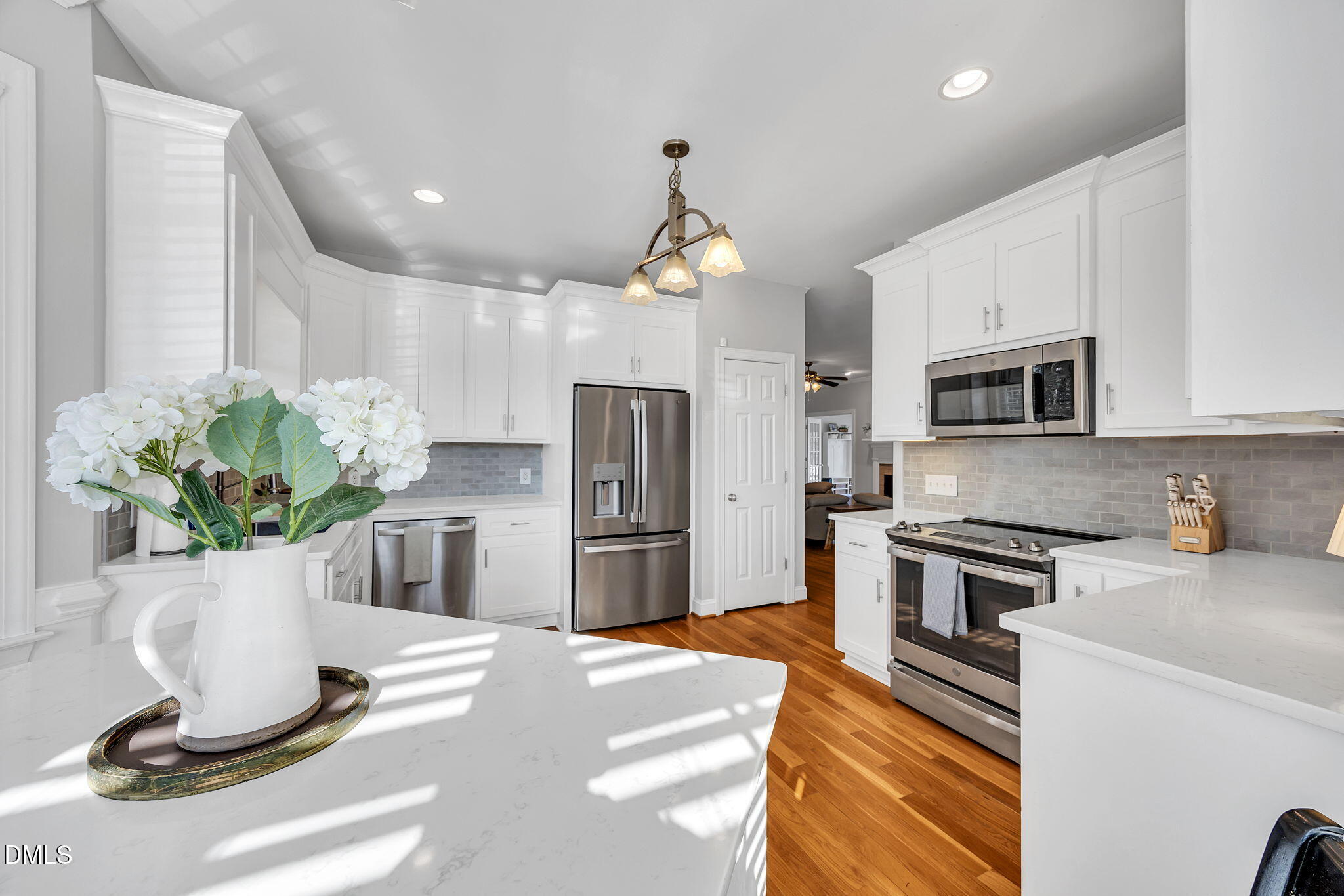 1869 Firetower Road Selma, NC 27576 - Photo 27 of 67 a kitchen with stainless steel appliances kitchen island granite countertop a refrigerator a stove a sink dishwasher and white cabinets with wooden floor
