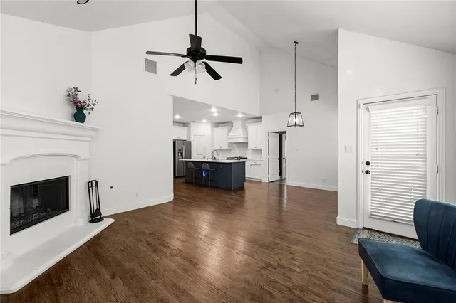 a view of a livingroom with a fireplace a ceiling fan and wooden floor
