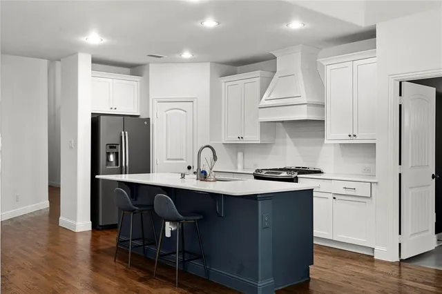 a kitchen with stainless steel appliances granite countertop a sink a stove a refrigerator and island with wooden floor