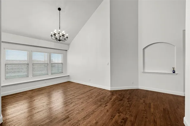 a view of empty room with wooden floor and window