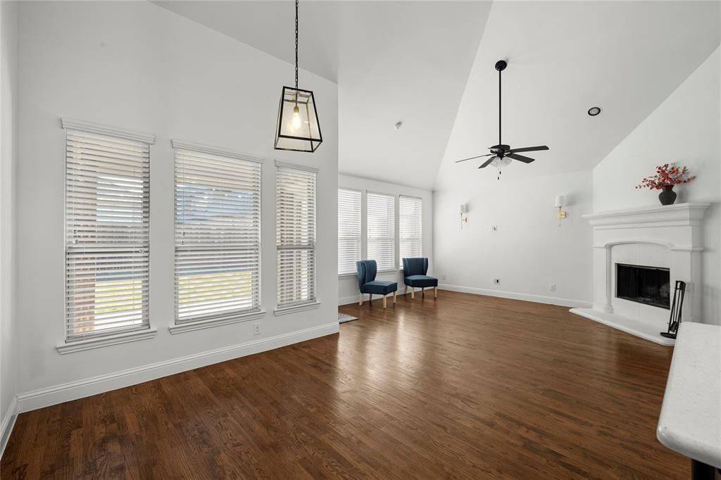 1102 Brigham Drive Forney, TX 75126 - Photo 10 of 30 Unfurnished living room with high vaulted ceiling, dark wood-style floors, a fireplace with raised hearth, and a ceiling fan