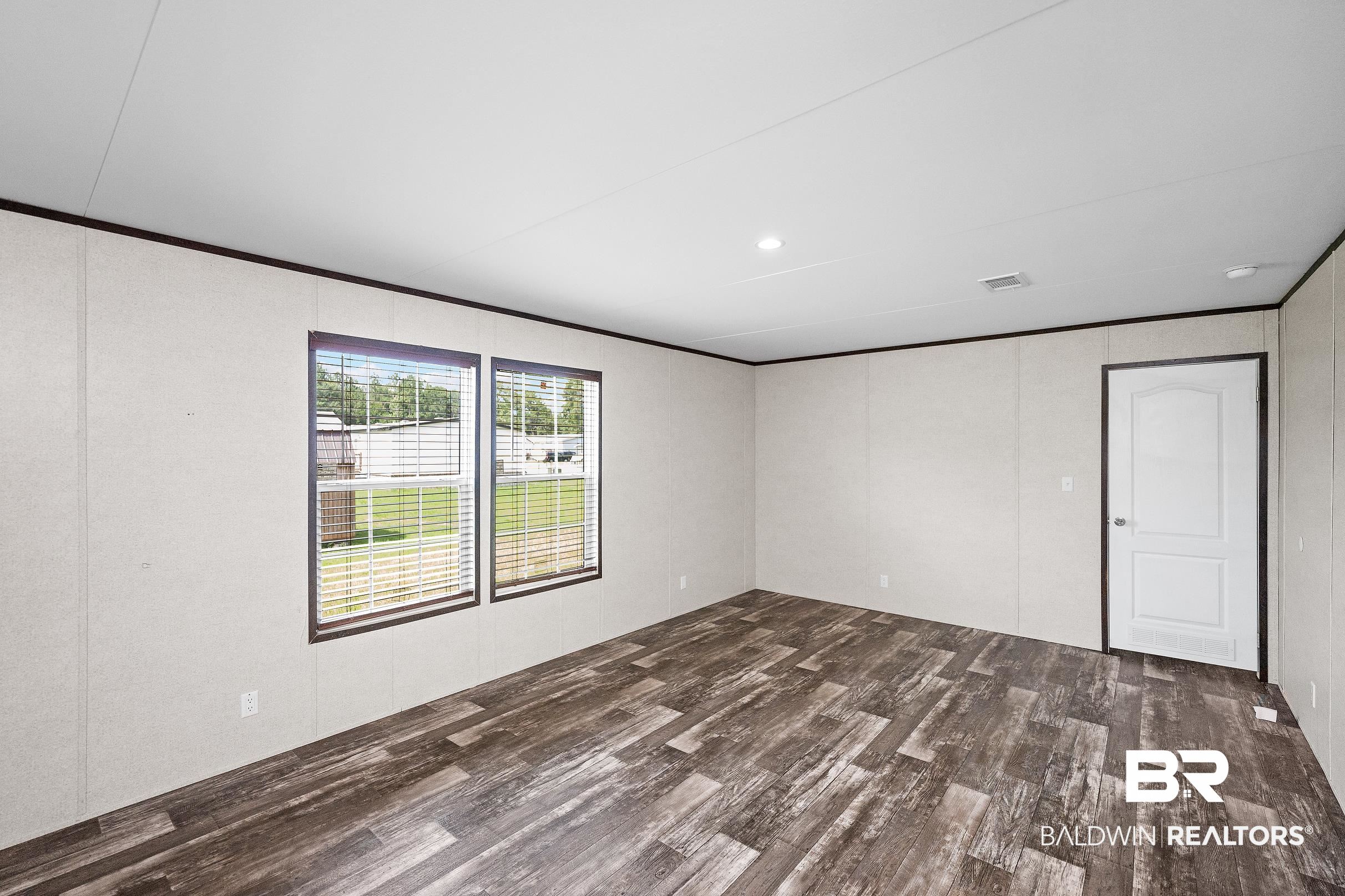 21601 Westside Loop Silverhill, AL 36576 - Photo 20 of 42 Spacious room featuring wood-finish flooring, two windows with blinds, a white paneled door, and recessed lighting