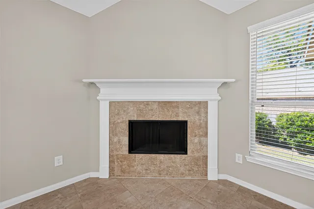 a view of an empty room with chandelier fan and fire place