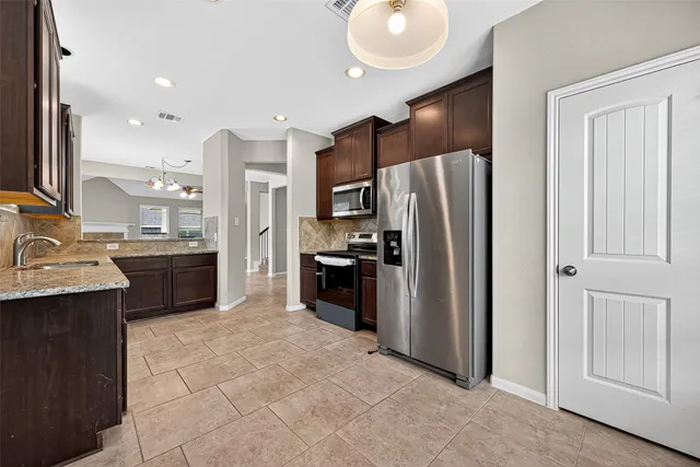 a kitchen with stainless steel appliances granite countertop a stove a sink and a microwave