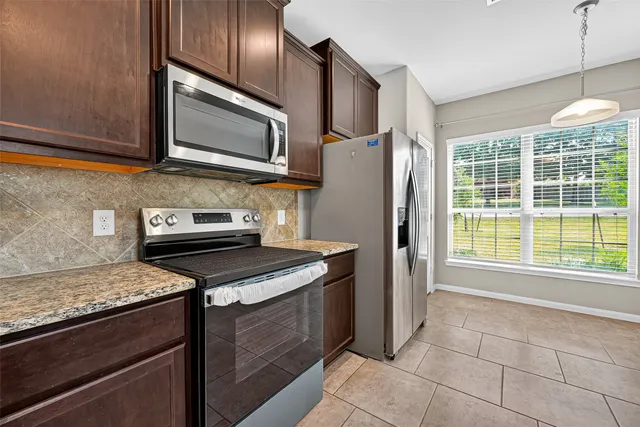 a kitchen with stainless steel appliances granite countertop a stove microwave and refrigerator