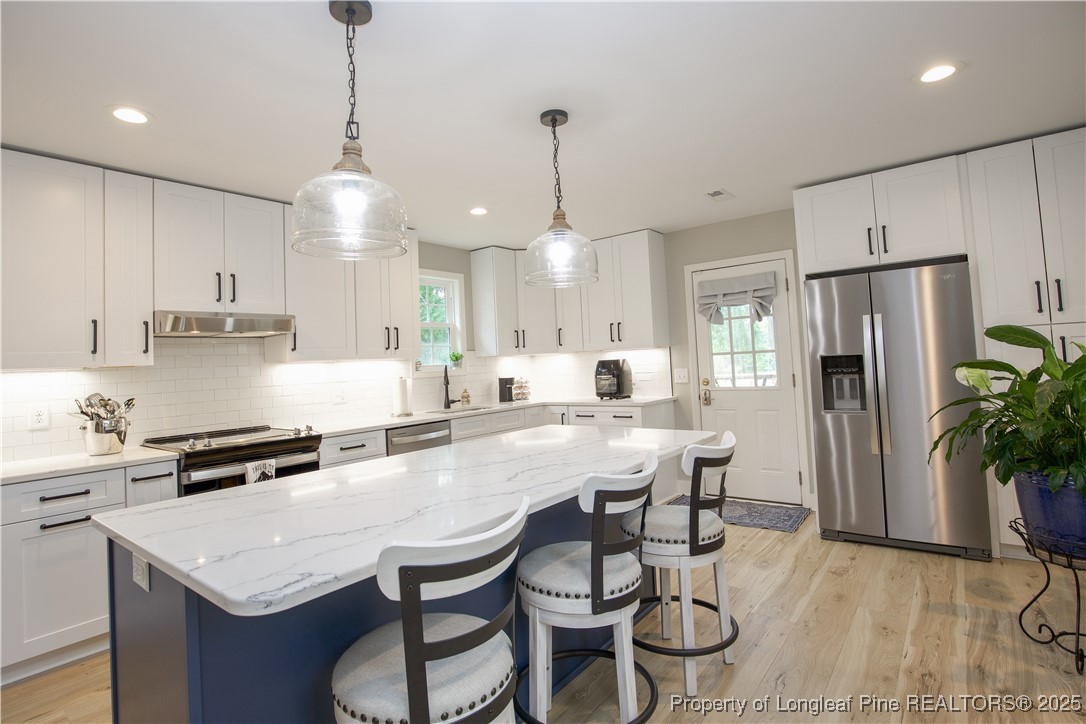 200 Cameron Avenue Vass, NC 28394 - Photo 48 of 50 a kitchen with stainless steel appliances granite countertop a kitchen island a stove a table and chairs in it