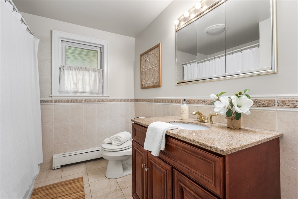 409 Haverhill Street Reading, MA 01867 - Photo 28 of 42 a bathroom with a granite countertop toilet sink and mirror