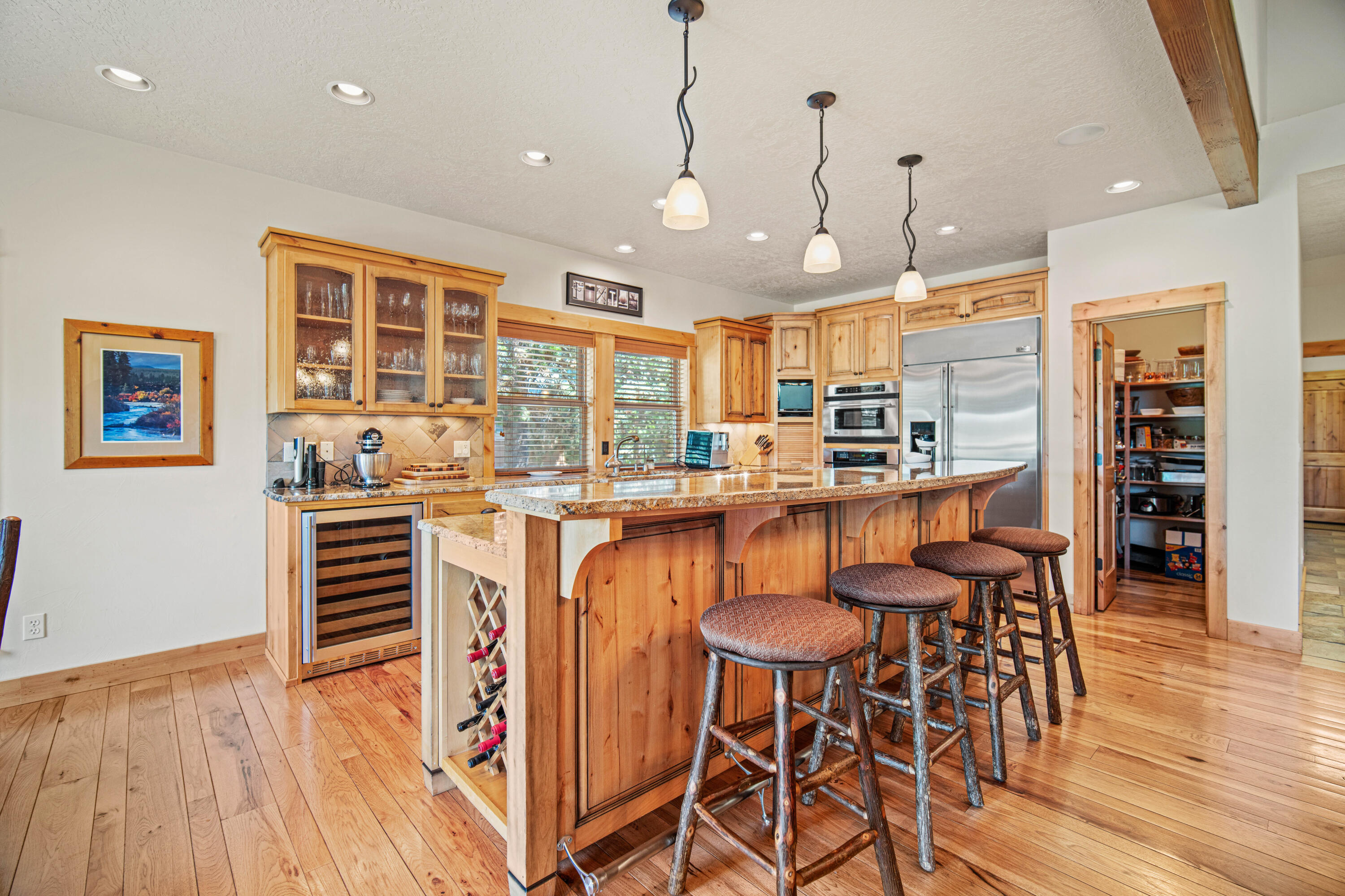 56689 Dancing Rock Loop Bend, OR 97707 - Photo 11 of 51 a kitchen with stainless steel appliances granite countertop a stove top oven a refrigerator a dining table and chairs with wooden floor