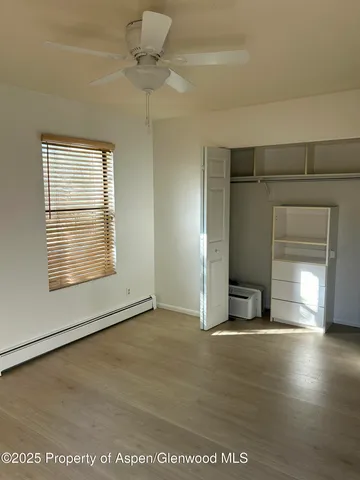 an empty room with wooden floor fan and windows