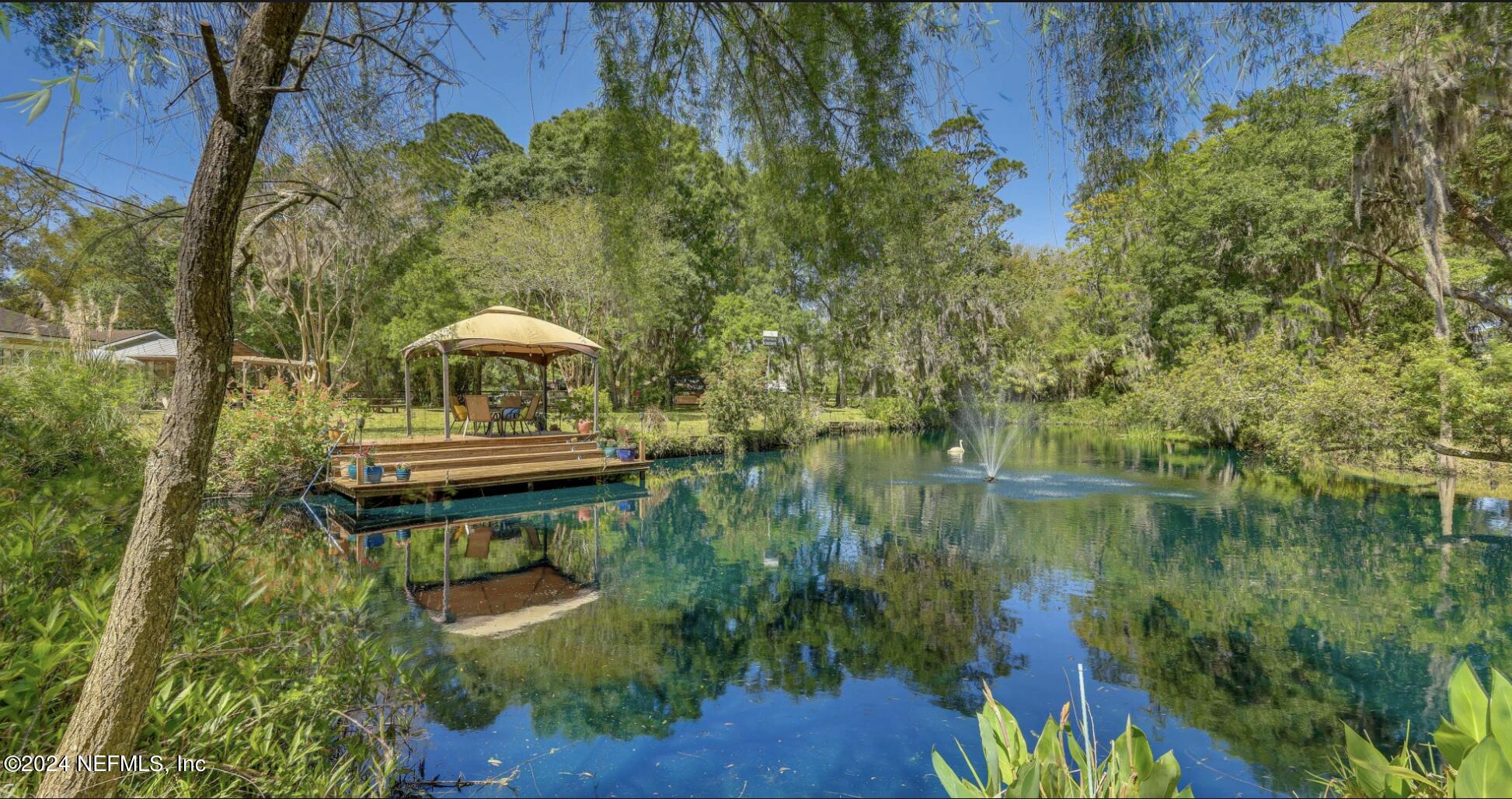 6070 Datil Pepper Road St. Augustine, FL 32086 - Photo 56 of 73 a backyard of a house with table and chairs under an umbrella