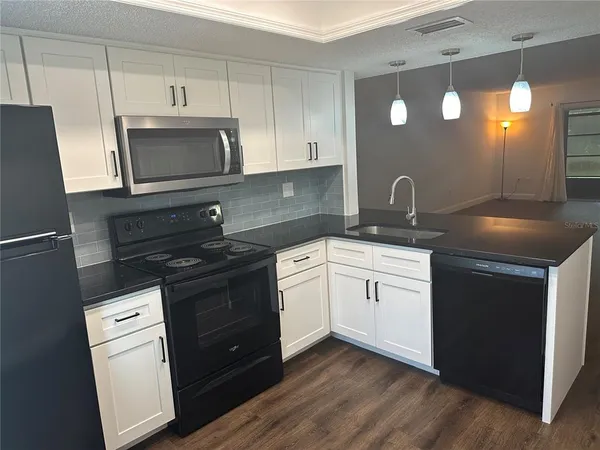 a kitchen with stainless steel appliances granite countertop a sink a stove and a wooden floor