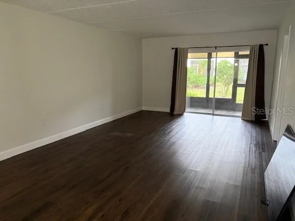 a view of an empty room with wooden floor and a window