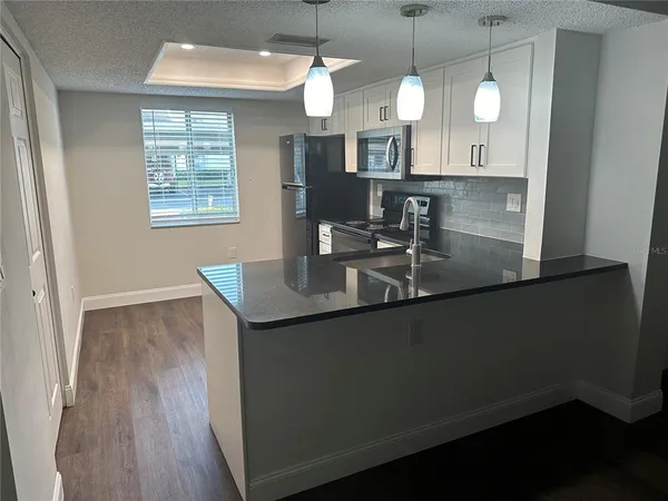 a kitchen with granite countertop a sink cabinets and wooden floor