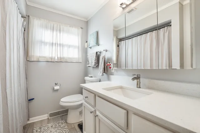 a bathroom with a sink a toilet and a window