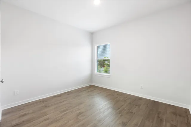 an empty room with wooden floor and window