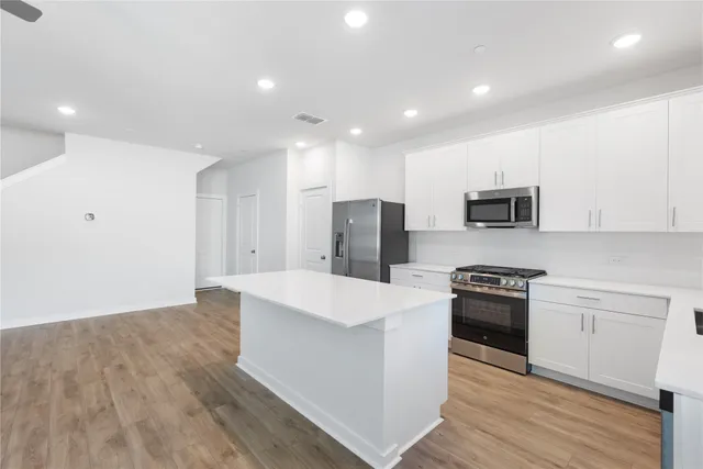 a large kitchen with stainless steel appliances granite countertop a stove a sink and a refrigerator