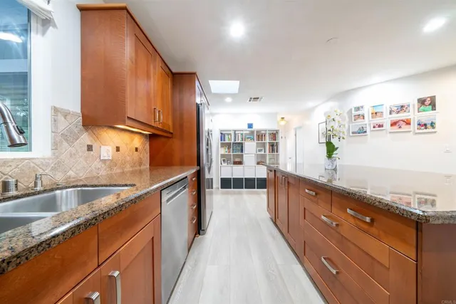a large kitchen with kitchen island granite countertop a large window and stainless steel appliances