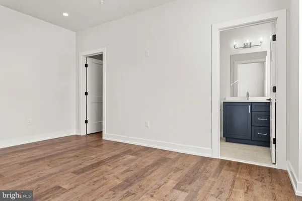 a view of an empty room with closet and wooden floor