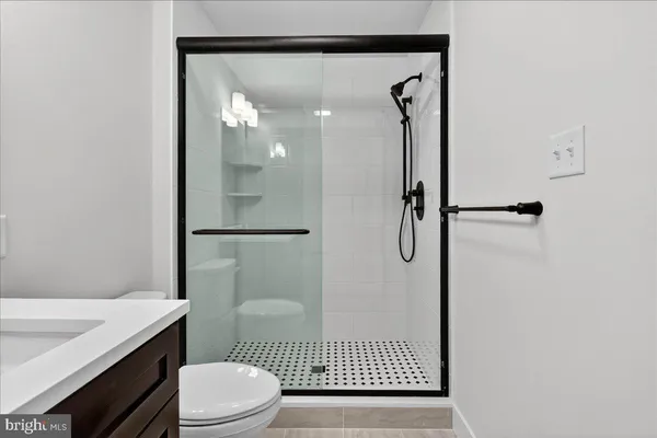 a bathroom with a granite countertop shower a toilet and a sink