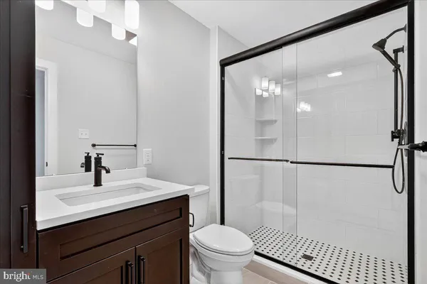 a bathroom with a sink a toilet a mirror and shower