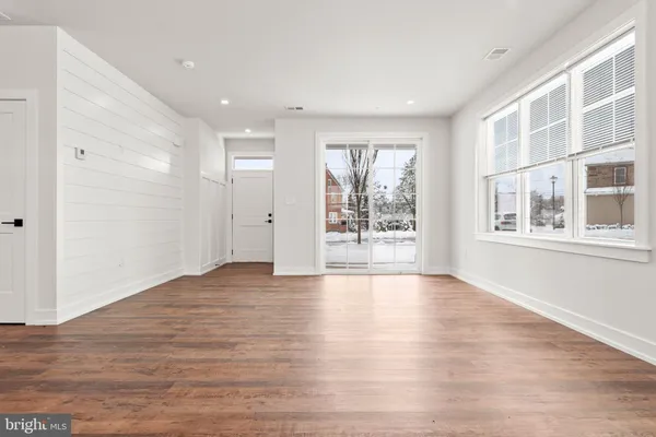 a view of an empty room with a window and wooden floor
