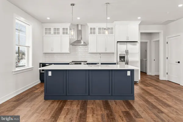 a kitchen with kitchen island granite countertop wooden floors and white cabinets