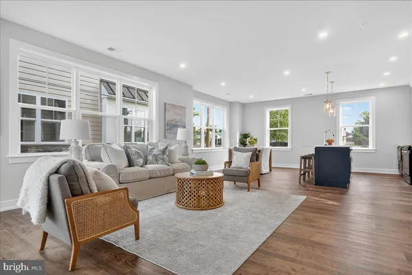 a living room with furniture a large window and wooden floor