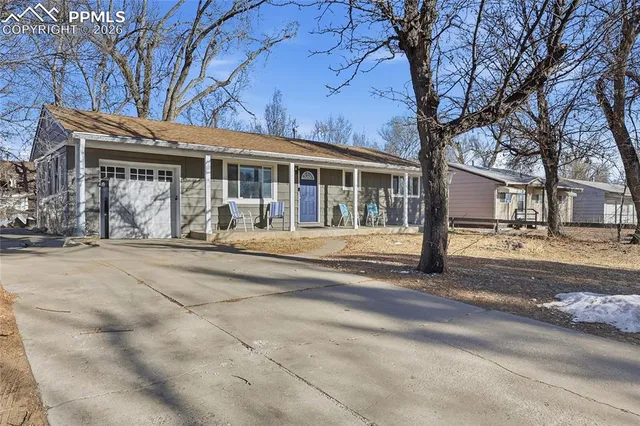 a front view of a house with a garden and trees