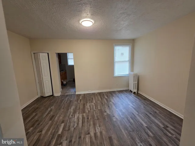 a view of an empty room with window and wooden floor