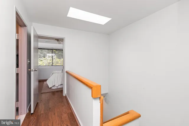 a view of a hallway with wooden floor and a bathroom