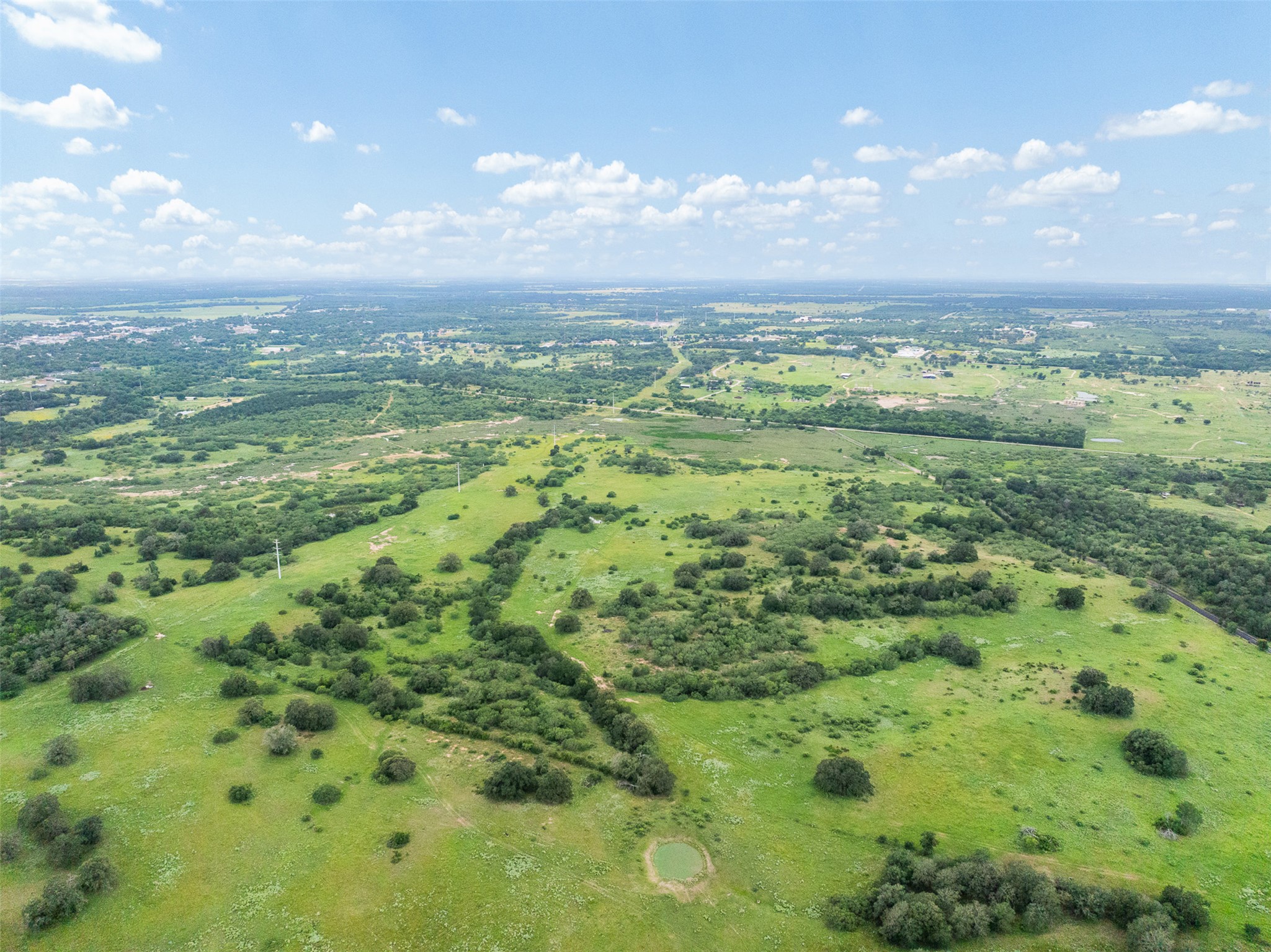 Tbd Lot 10 Tbd Road Luling, TX 78648 - Photo 7 of 10 Vast green acreage unfolds under a wide-open sky, offering a serene pastoral landscape.