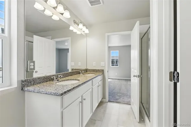a bathroom with a granite countertop sink a mirror and a shower