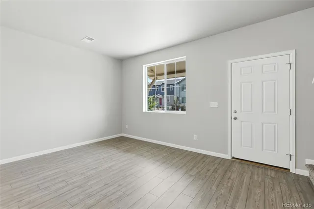 an empty room with wooden floor and windows