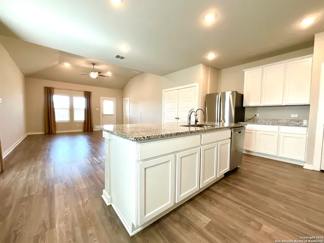 a large kitchen with stainless steel appliances granite countertop a lot of counter space and wooden floors