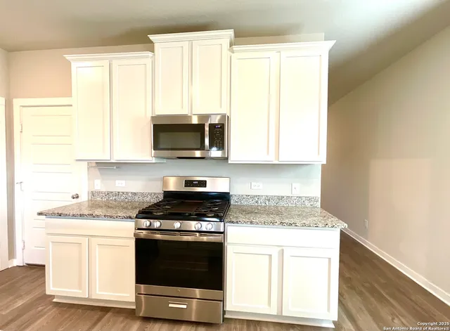 a kitchen with granite countertop a stove a sink and a microwave