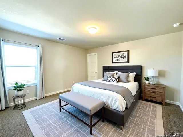 a spacious bedroom with a bed a couch and potted plant