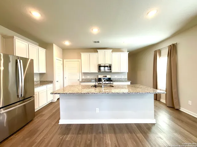 a view of kitchen with stainless steel appliances granite countertop a refrigerator a stove and a wooden floors
