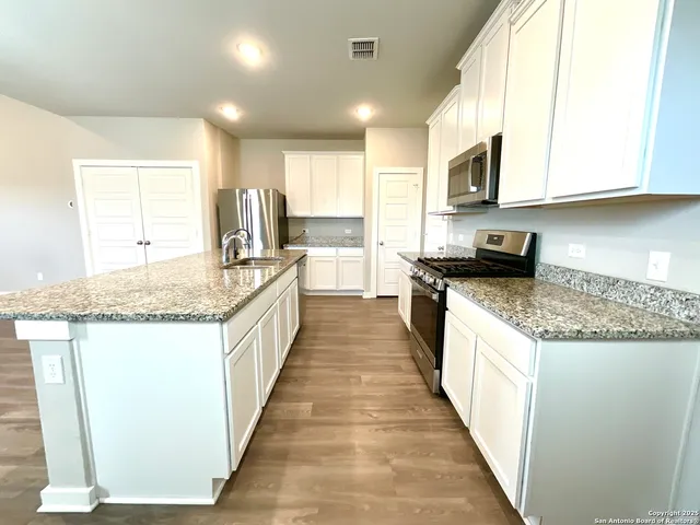 a large kitchen with stainless steel appliances granite countertop a stove a sink and a microwave