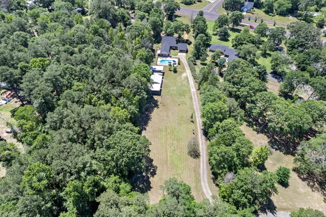 an aerial view of residential house with outdoor space and trees all around