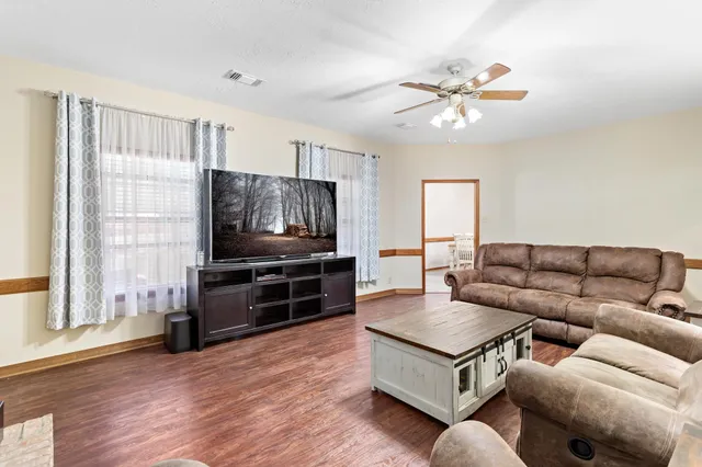 a living room with furniture a flat screen tv and a window