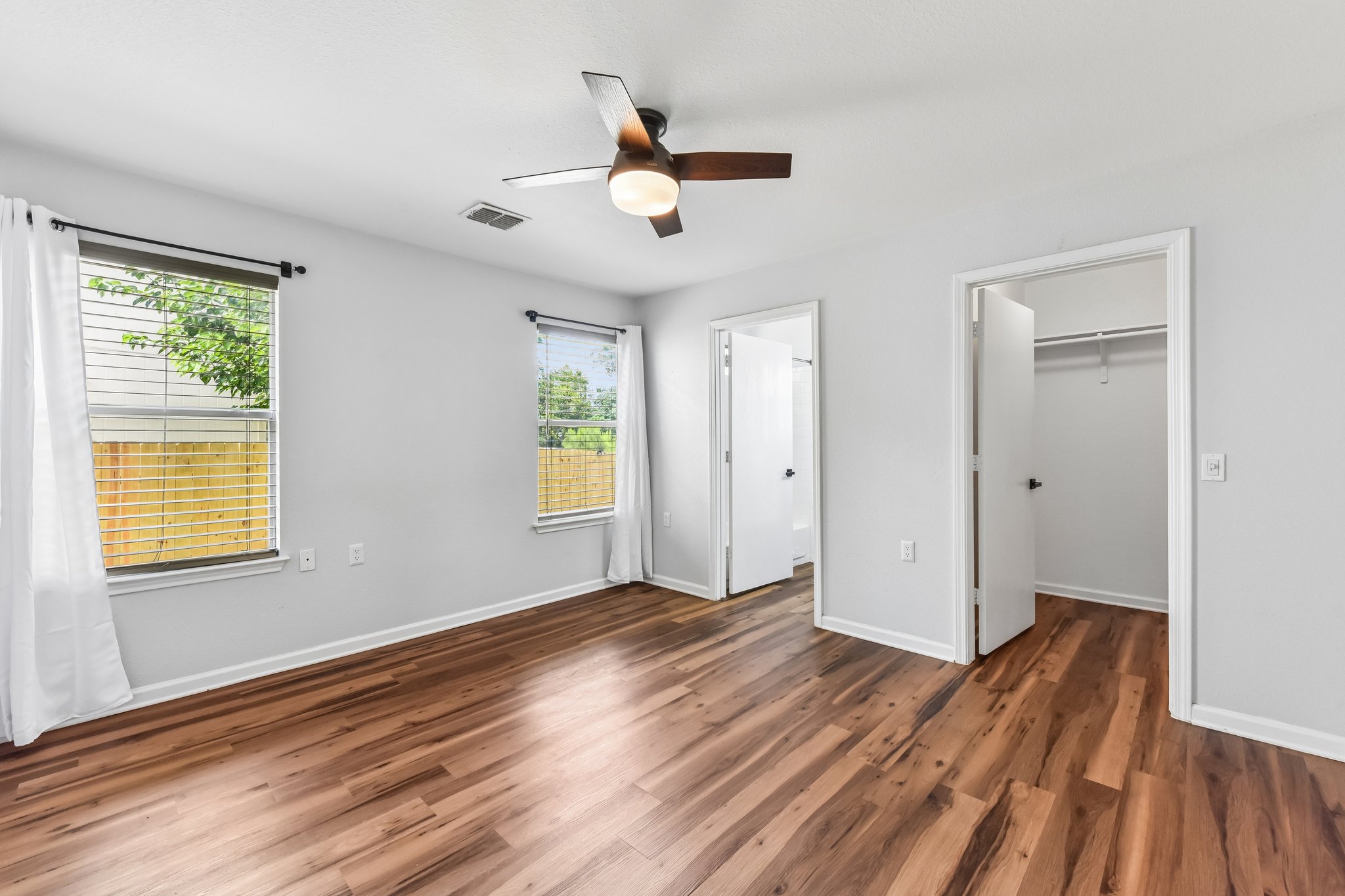 5405 Rusk Court Austin, TX 78723 - Photo 21 of 40 A comfortable bedroom carpet free with en un-suite and walk-in-closet and a modern ceiling fan.