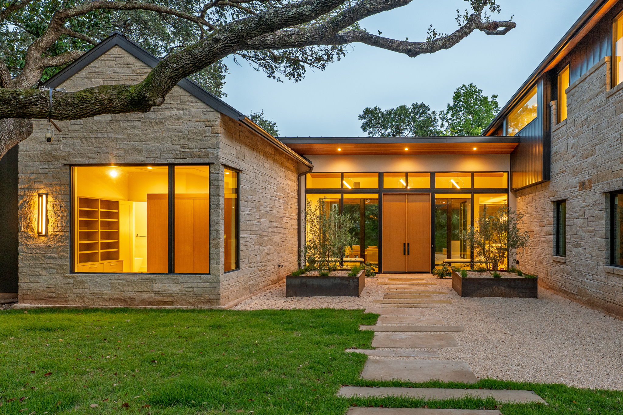 405 Honeycomb Ridge Austin, TX 78746 - Photo 1 of 15 A striking contemporary residence featuring a stone facade and floor-to-ceiling windows.