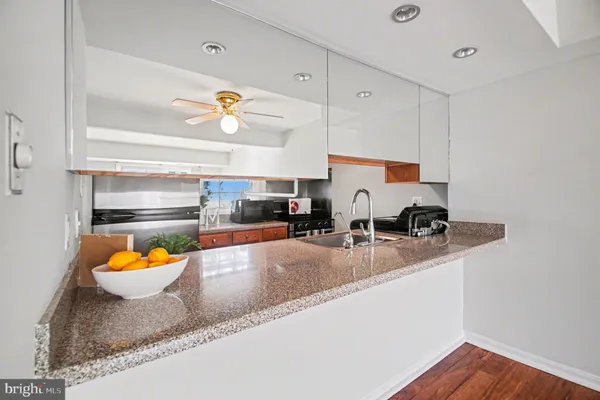 a kitchen with stainless steel appliances granite countertop a sink a stove and a granite counter tops with white cabinets